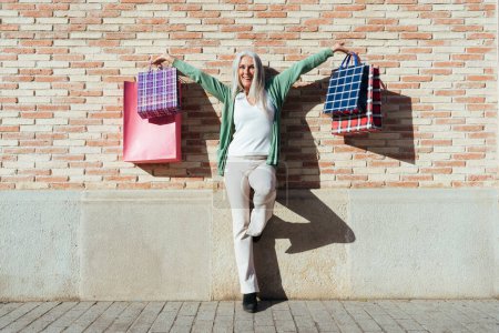 Photo for Beautiful senior woman with silver gray hair shopping outdoors in the city - Attractive cheerful mature female having fun, shopping and bonding, concepts about elderly lifestyle - Royalty Free Image