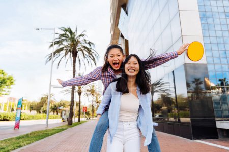 Photo for Happy beautiful chinese women friends bonding outdoors in the city - Playful pretty asian female adults meeting and having fun outside, concepts about lifestyle and friendship - Royalty Free Image