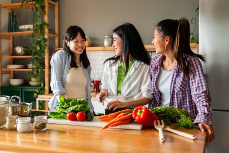 Photo for Happy beautiful chinese women friends bonding at home and cooking delicious meal together- Playful pretty asian female adults meeting and having fun at home, concepts about lifestyle, domestic life and friendship - Royalty Free Image