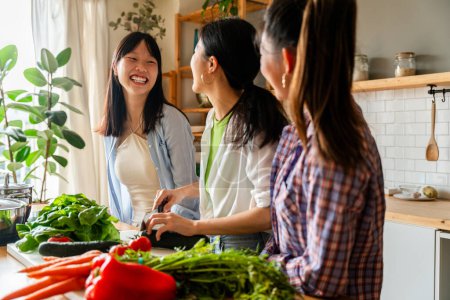 Téléchargez les photos : Bonnes amies chinoises heureuses se lient à la maison et cuisinent de délicieux repas ensemble- Jolies adultes asiatiques ludiques se rencontrent et s'amusent à la maison, concepts sur le mode de vie, la vie domestique et l'amitié - en image libre de droit