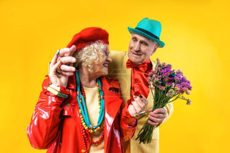Photo for Beautiful senior old couple wearing fancy party clothes acting in studio on a colored background. Conceptual image about third age and seniority, old people feeling young inside. - Royalty Free Image