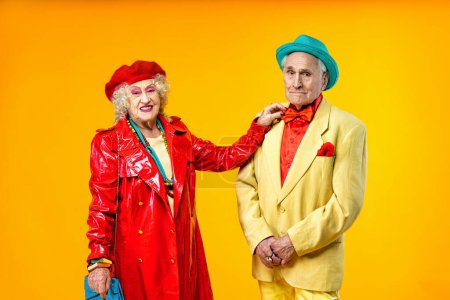 Foto de Hermosa pareja de ancianos vistiendo ropa de fiesta de lujo actuando en el estudio sobre un fondo de color. Imagen conceptual sobre la tercera edad y la antigüedad, los ancianos sintiéndose jóvenes por dentro. - Imagen libre de derechos