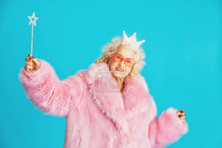 Foto de Hermosa anciana mayor con ropa de fiesta de lujo actuando sobre un fondo de color en el estudio - Imagen conceptual sobre la tercera edad y la antigüedad, las personas mayores se sienten jóvenes dentro. - Imagen libre de derechos