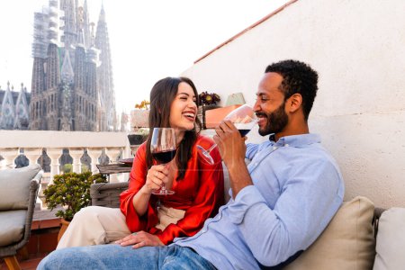 Téléchargez les photos : Multiracial beau couple heureux d'amoureux datant sur le balcon sur le toit à la Sagrada Familia, Barcelone - Les gens multiethniques ayant apéritif romantique sur une terrasse avec vue sur la ville, concepts sur le tourisme et le mode de vie des gens - en image libre de droit
