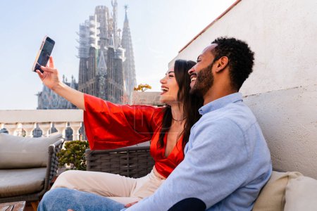 Foto de Multiracial hermosa pareja feliz de amantes citas en el balcón de la azotea en Sagrada Familia, Barcelona - Personas multiétnicas teniendo encuentro romántico en una terraza con vista a la ciudad, conceptos sobre el turismo y el estilo de vida de las personas - Imagen libre de derechos
