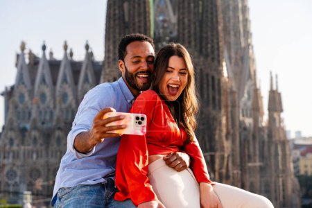 Photo for Multiracial beautiful happy couple of lovers dating on rooftop balcony at Sagrada Familia, Barcelona - Multiethnic people having romantic meeting on a terrace with city view , concepts about tourism and people lifestyle - Royalty Free Image