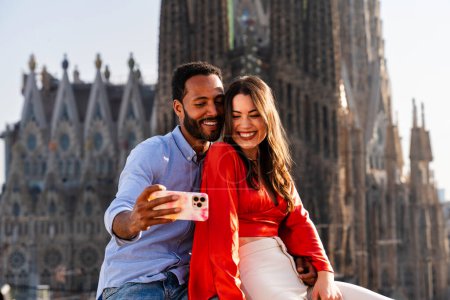 Téléchargez les photos : Multiracial beau couple heureux d'amoureux datant sur le balcon sur le toit à la Sagrada Familia, Barcelone - Les gens multiethniques ayant une réunion romantique sur une terrasse avec vue sur la ville, concepts sur le tourisme et le mode de vie des gens - en image libre de droit