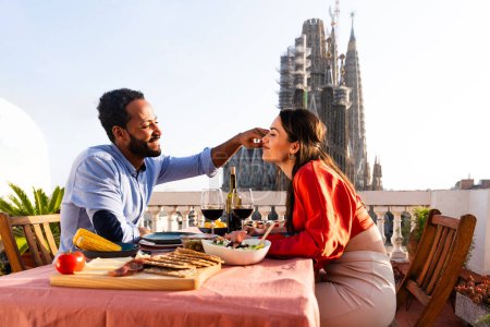 Téléchargez les photos : Multiracial beau couple heureux d'amoureux datant sur le balcon sur le toit à la Sagrada Familia, Barcelone - Les gens multiethniques ayant dîner apéritif romantique sur une terrasse avec vue sur la ville, concepts sur le tourisme et le mode de vie des gens - en image libre de droit