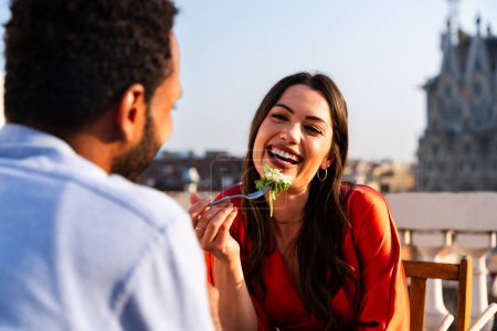 Photo for Multiracial beautiful happy couple of lovers dating on rooftop balcony at Sagrada Familia, Barcelona - Multiethnic people having romantic aperitif dinner on a terrace with city view , concepts about tourism and people lifestyle - Royalty Free Image