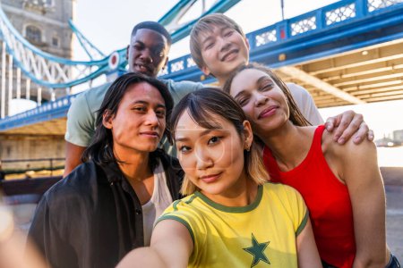 Téléchargez les photos : Groupe multiracial de jeunes amis heureux qui se lient d'amitié à Londres - Les adolescents multiethniques se rencontrent et s'amusent dans la région de Tower Bridge, Royaume-Uni - Concepts sur le mode de vie des jeunes, les voyages et le tourisme - en image libre de droit