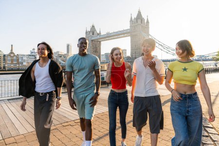 Foto de Grupo multirracial de jóvenes amigos felices que se unen en la ciudad de Londres - Estudiantes adolescentes multiétnicos que se reúnen y se divierten en el área de Tower Bridge, Reino Unido - Conceptos sobre estilo de vida juvenil, viajes y turismo - Imagen libre de derechos