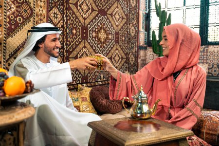 Foto de Parejas jóvenes de Emirati pasan tiempo en un café tradicional árabe. Hombre y mujer usando kandura y abaya de Dubai conversando juntos. - Imagen libre de derechos