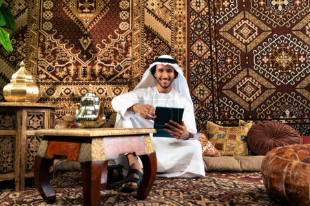 Photo for Man from emirati wearing kandura outfit spending time in an arabian traditional house in Dubai - Royalty Free Image