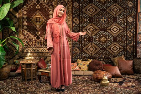 Foto de Hermosa mujer joven vistiendo abaya de color interior en un café tradicional árabe - Imagen libre de derechos