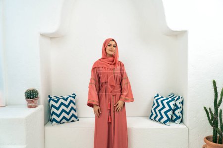 Téléchargez les photos : Belle jeune femme portant abaya coloré à l'intérieur dans un café arabe traditionnel - en image libre de droit