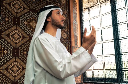 Téléchargez les photos : Homme d'emirati en tenue de kandura passant du temps dans une maison traditionnelle arabe à Dubaï - en image libre de droit