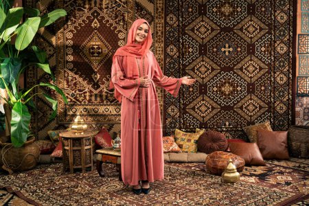 Téléchargez les photos : Belle jeune femme portant abaya coloré à l'intérieur dans un café arabe traditionnel - en image libre de droit