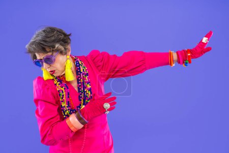 Happy and funny senior old woman wearing fashinable clothing on colorful background- Modern cool fancy grandmother portrait, concepts about elderly and older people