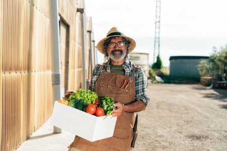 Foto de Hombre mayor agricultor que trabaja en su granja y invernadero. Concepto sobre agricultura, industria agrícola y estilo de vida saludable durante la edad de antigüedad - Imagen libre de derechos