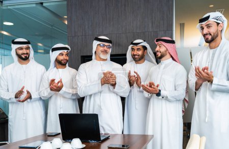 Foto de Grupo de empresarios árabes corporativos reunidos en la oficina - Empresarios de Oriente Medio que usan emirati kandora trabajando en una sala de reuniones, Dubai - Imagen libre de derechos