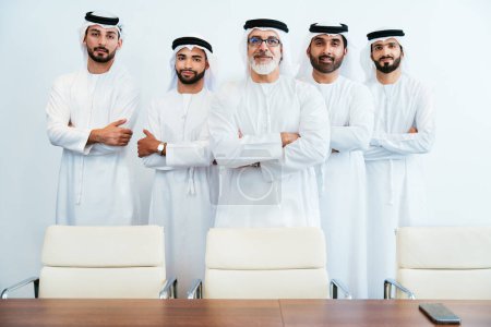 Photo for Group of corporate arab businessmen meeting in the office - Middle-eastern businesspeople wearing emirati kandora working in a meeting room, Dubai - Royalty Free Image