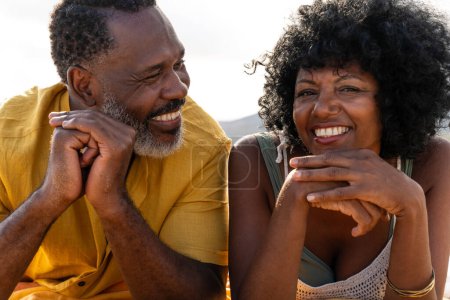 Photo for Beautiful mature black couple of lovers dating at the seaside - Married african middle-aged couple bonding and having fun outdoors, concepts about relationship, lifestyle and quality of life - Royalty Free Image