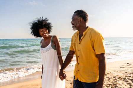Téléchargez les photos : Beau couple noir mature d'amoureux sortir ensemble au bord de la mer Marié africain d "âge moyen liaison et avoir du plaisir en plein air, concepts sur la relation, le mode de vie et la qualité de vie - en image libre de droit