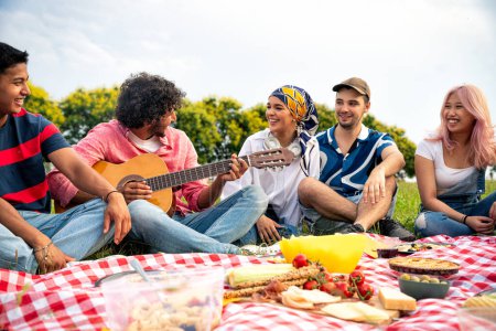 Foto de Grupo de adolescentes multiétnicos que pasan tiempo al aire libre en un picnic en el parque. Concepto sobre generación z, estilo de vida y amistad - Imagen libre de derechos