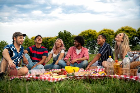 Téléchargez les photos : Groupe d'adolescents multiethniques passant du temps en plein air sur un pique-nique au parc. Concept sur la génération z, mode de vie et amitié - en image libre de droit