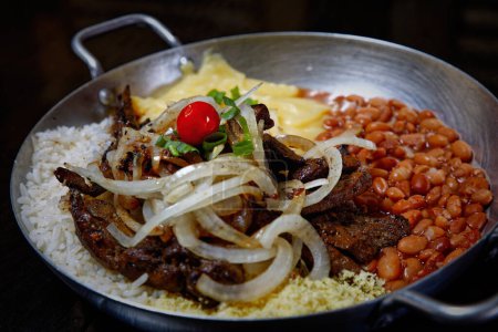 Foto de Olla de esmalte con frijoles, arroz, puré de papas, carne frita y rodajas de cebolla - Imagen libre de derechos