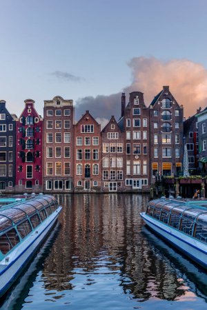 Blick auf die tanzenden Häuser am Damrak-Kanal in Amsterdam bei Sonnenuntergang