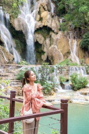 Photo for Young Asian woman standing on the wooden walkway in the Kuang Si Waterfall Popular attractions of Lung Prabang, Laos - Royalty Free Image