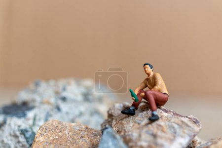 Photo for Miniature people , A young man sipping beer while sitting on the rock - Royalty Free Image