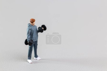 Foto de Personas en miniatura, Fit Young Man Levantando pesas contra fondo gris - Imagen libre de derechos