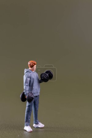 Foto de Personas en miniatura, Fit Young Man Levantando pesas contra fondo verde - Imagen libre de derechos