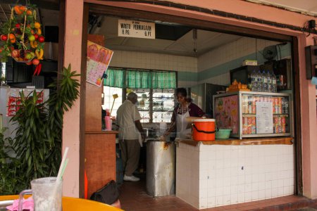 Téléchargez les photos : Ipoh, Perak, Malaisie - Novembre 2012 : Personnes travaillant dans une petite cuisine dans un étal de restauration de rue dans la ville d'Ipoh. - en image libre de droit