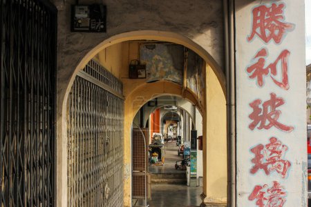 Foto de Georgetown, Penang, Malasia - Noviembre 2012: Arcos antiguos de un callejón en la acera alineados con tiendas antiguas y santuarios en el sitio del patrimonio mundial de George Town en Penang. - Imagen libre de derechos