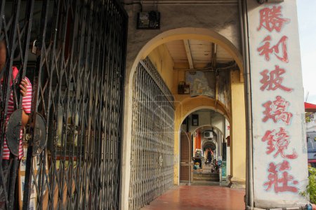 Foto de Georgetown, Penang, Malasia - Noviembre 2012: Arcos antiguos de un callejón en la acera alineados con tiendas antiguas y santuarios en el sitio del patrimonio mundial de George Town en Penang. - Imagen libre de derechos
