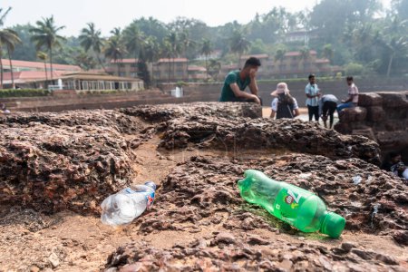 Téléchargez les photos : Candolim, Goa, Inde - Janvier 2023 : Bouteilles en plastique et déchets jetés sur le mur de briques latérite d'un ancien fort portugais à Sinquerim. - en image libre de droit