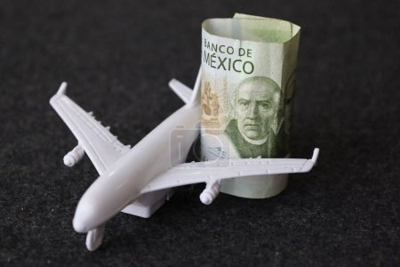 zusammengerollte mexikanische Banknote von 200 Pesos und Figur eines weißen Flugzeugs
