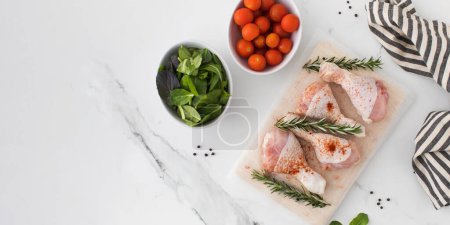 Photo for Raw chicken legs with spices and rosemary sprigs on a wooden cutting board. Farm products. Copy space - Royalty Free Image