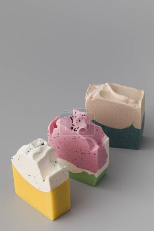 Stücke in verschiedenen Formen und Farben aus handgemachter Seife auf grauem Hintergrund. Das Konzept der Naturkosmetik, Hygiene.