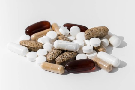 Téléchargez les photos : Une variété de pilules et de vitamines dans une pile sur un fond blanc. Le concept de médecine, les médicaments. - en image libre de droit