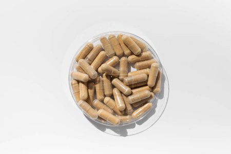 Téléchargez les photos : Les capsules avec des vitamines ou un complément alimentaire sont brunes sur fond blanc. Le concept de médecine, les médicaments. - en image libre de droit