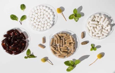 Foto de Varias vitaminas, tabletas y suplementos dietéticos con formulaciones naturales sobre un fondo blanco. Productos farmacéuticos - Imagen libre de derechos