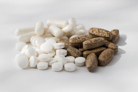 Téléchargez les photos : Une variété de pilules et de vitamines dans une pile sur un fond blanc. Le concept de médecine, les médicaments. - en image libre de droit
