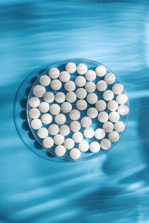 Téléchargez les photos : Pilules rondes blanches sur fond bleu. Le concept de pilules, minéraux et vitamines. - en image libre de droit