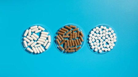 Verschiedene Vitamine, Tabletten und Nahrungsergänzungsmittel auf blauem Hintergrund. Das Konzept der Medizin.