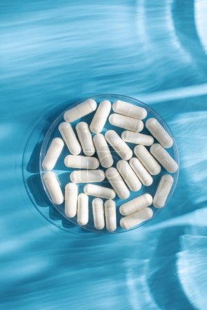 White medicinal capsules, vitamins or dietary supplements in close-up on a blue background. The concept of medicine.
