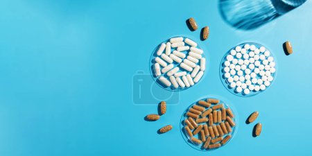 Verschiedene Vitamine, Tabletten und Nahrungsergänzungsmittel auf blauem Hintergrund. Das Konzept der Medizin. Kopierraum